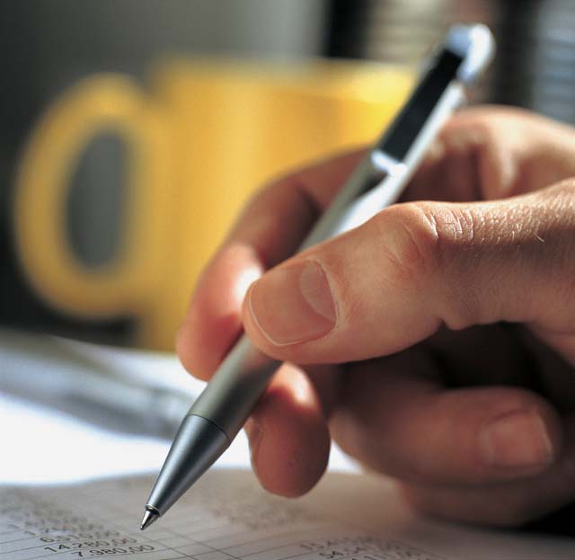 Hand Signing Document Hand holding pen signing document with yellow mug
