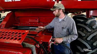 Titan Machinery service tech demonstrating maintenance on a Case IH 2388