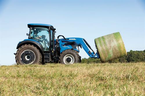 New Holland T5.130 Tractor in field with hay bale spears